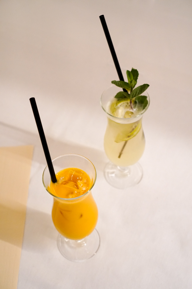 Two house drinks: a mango lassi and a fresh mint lemonade in tall glasses.
